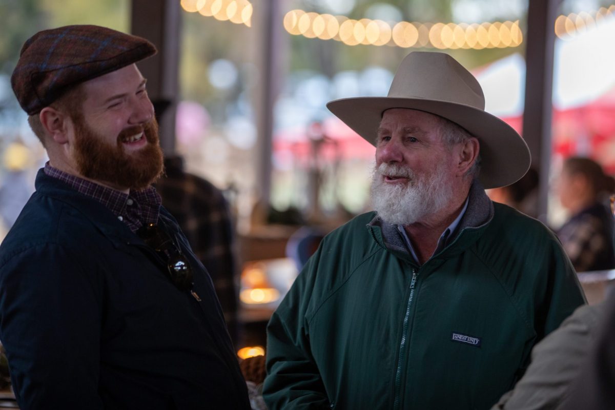 Two visitors talking and laughing beneath strings of lights at Homestead