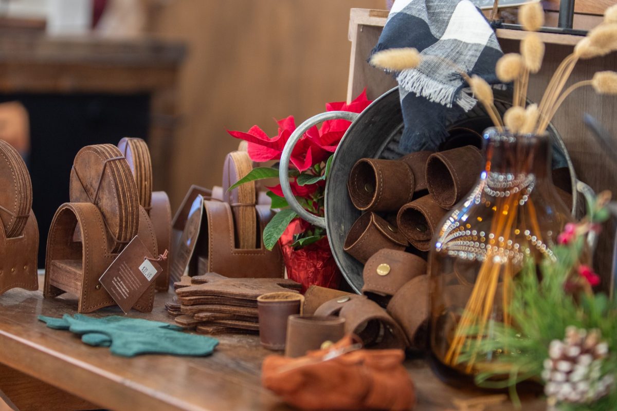 Handmade leather goods and Christmas greenery on a market table at Homestead